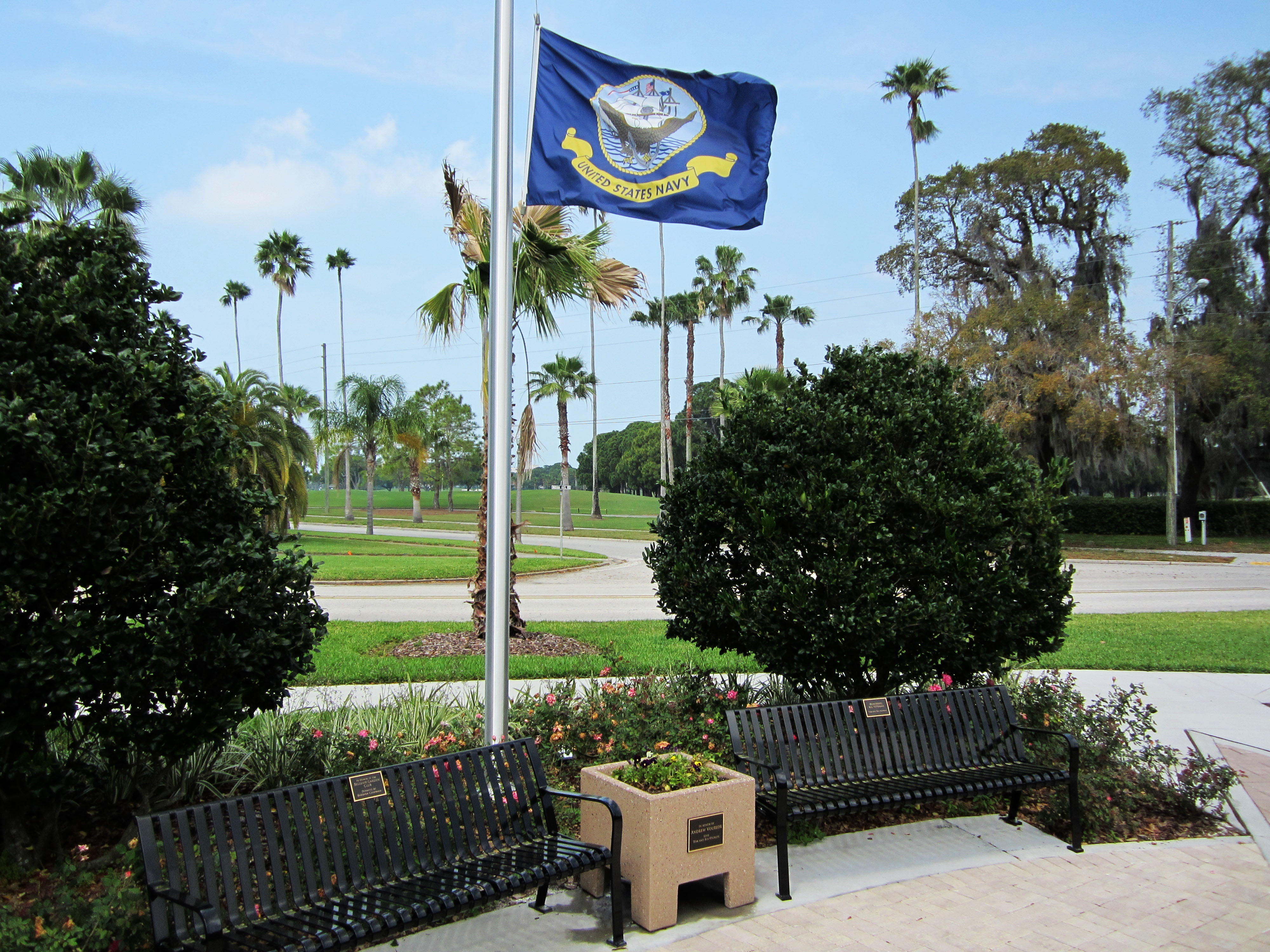 A flag for the United States Navy flies a half staff next to two benches in Hunter Memorial Park