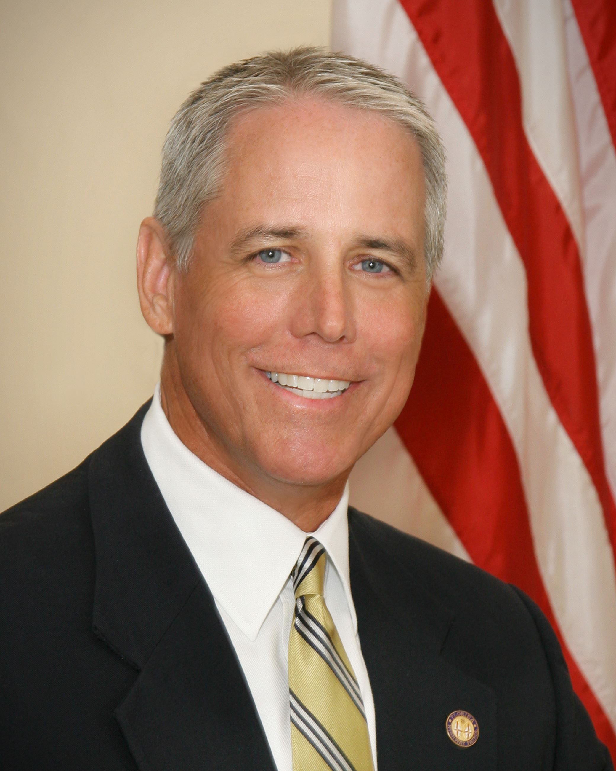 Mayor Mike Wilkinson smiling in front of an American flag.